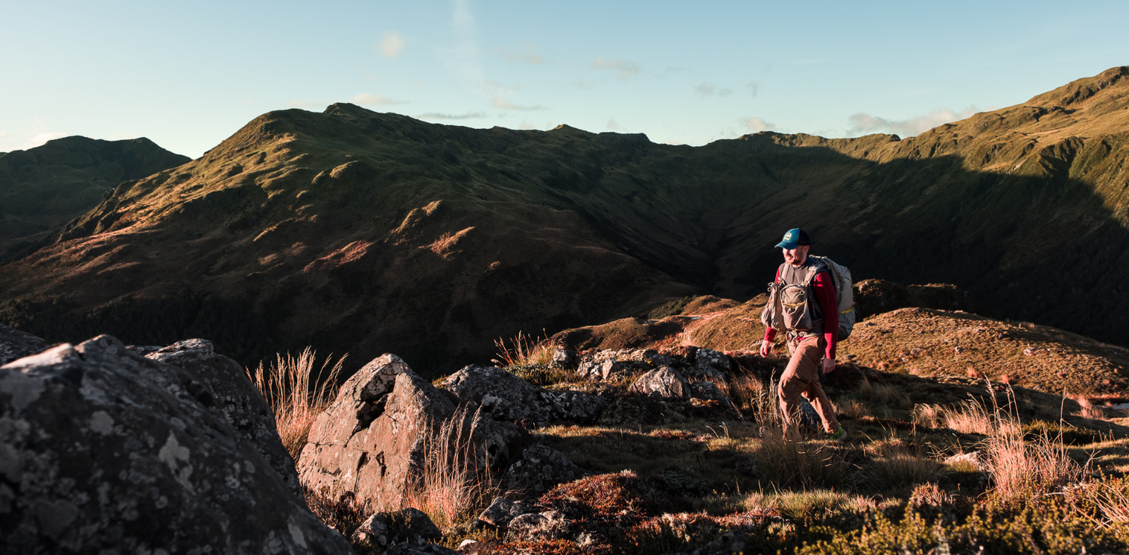 A man is walking in the mountains in New Zealand with Aarn hiking backpack. 