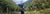 A woman is standing, looking at the view, next to a lake, in Fiordland National Park. She's hiking and packrafting, and wear an Aarn Peak aspiration. 