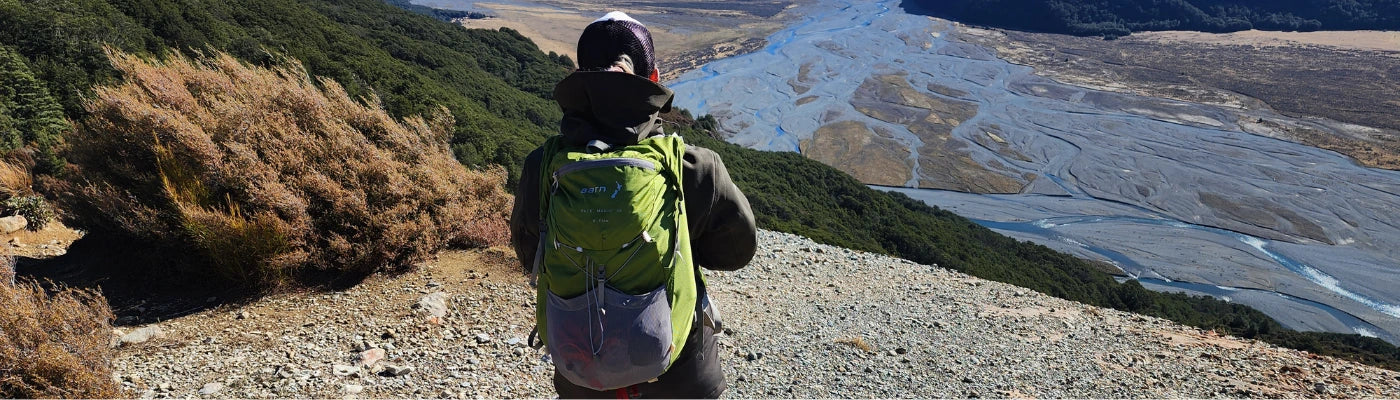 A woman is hiking with her Aarn Pace Magic fastpack. She is admiring the view of the Waimakariri river in New Zealand. 