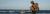 A woman is hiking on a beach, next to the ocean, with her Aarn hiking pack.