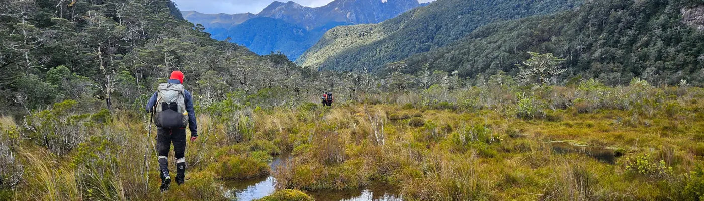 A man is walking through the backcountry in New Zealand. He is wearing an Aarn Mountain magic hiking pack. 